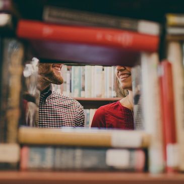 A picture of two smiling faces in between a two shelves of books