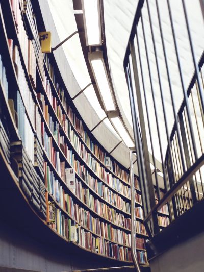 Curved bookshelf filled with books beside a staircase.