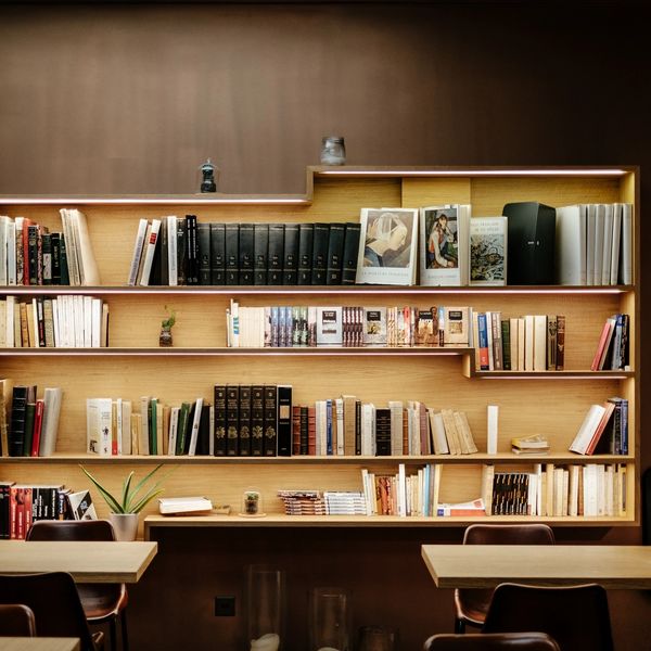 Cozy bookshelf with books and seating in a warm-lit room.