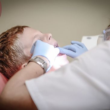 A close-up of a children's dental visit. Dentist examining the child’s teeth during a checkup.