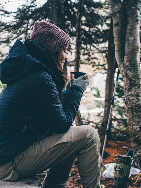 Person in winter clothes enjoying a hot drink outdoors.