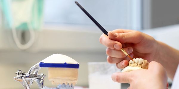 Person working on dental mold with a brush.