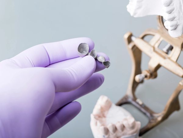 Faceless dentist in medical gloves cleaning teeth of dental jaw model
