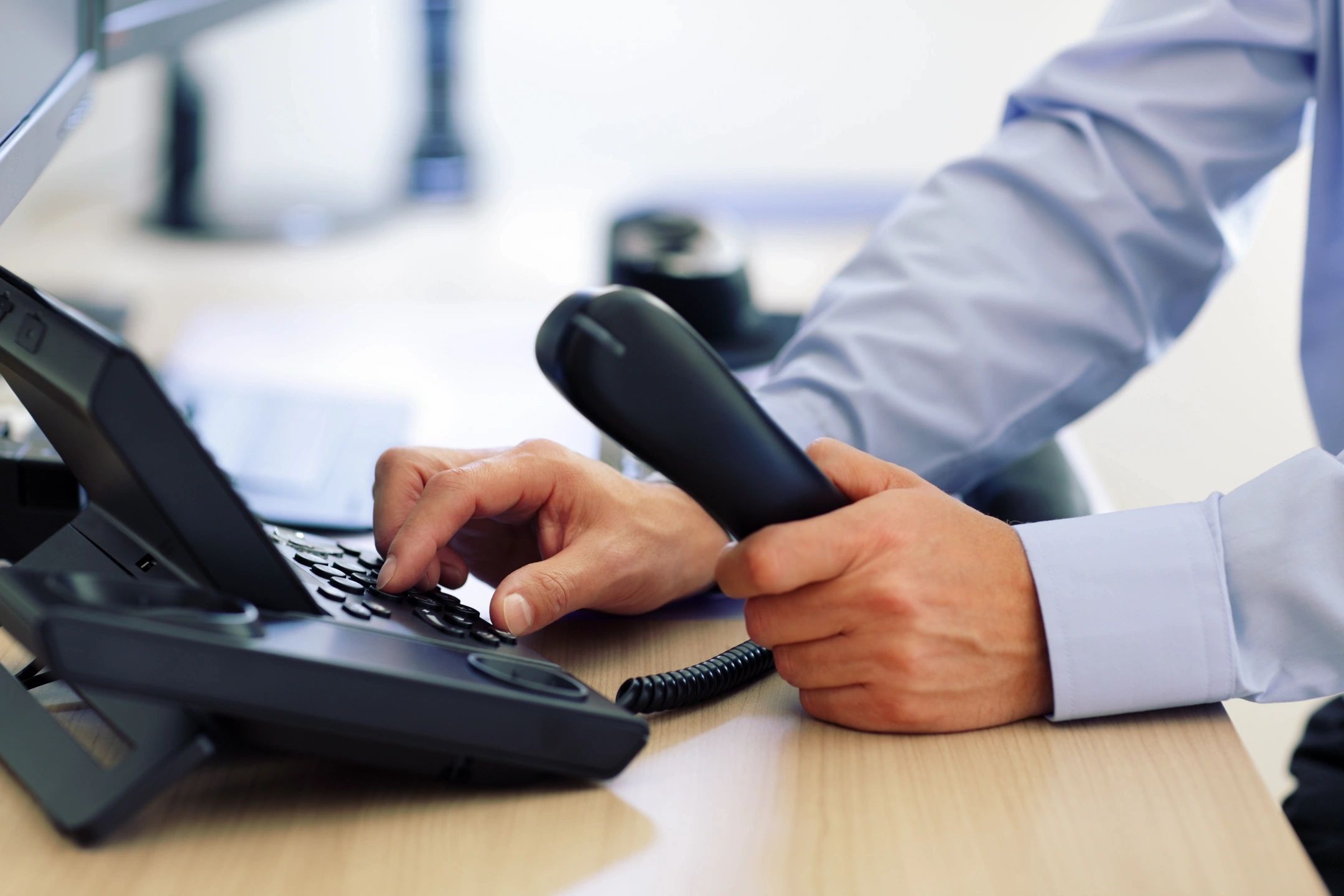 Person holding handset and dialing phone