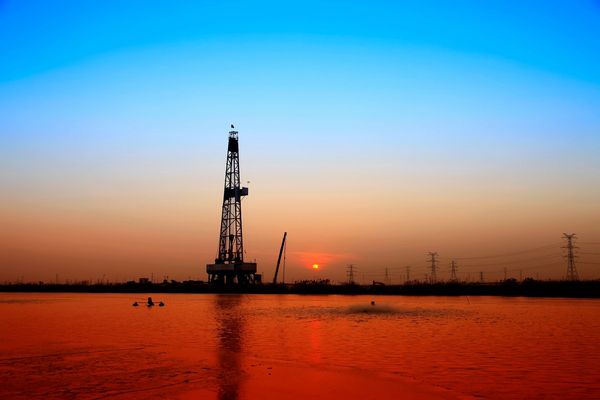 Oil rig at sunset with vibrant sky colors.