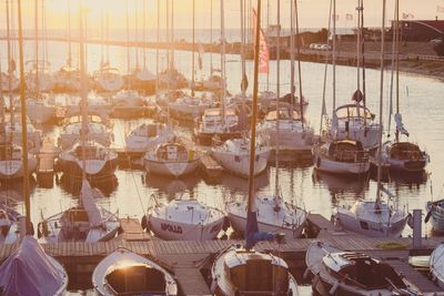 Sunset view of sailboats docked in a marina with calm waters.
