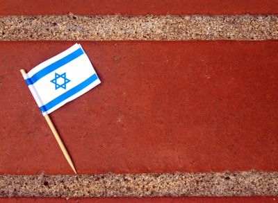 Small Israeli flag resting on a brick surface.