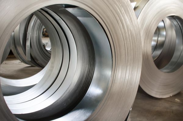 Coiled metal sheets stacked in an industrial setting.