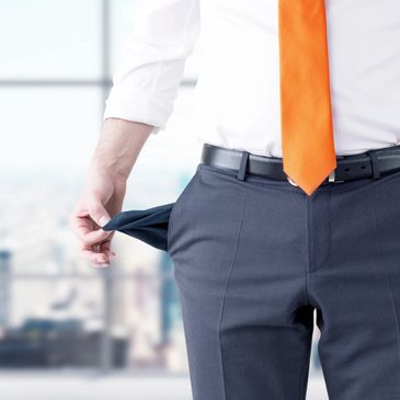 Businessman showing empty pockets, symbolizing financial trouble.
