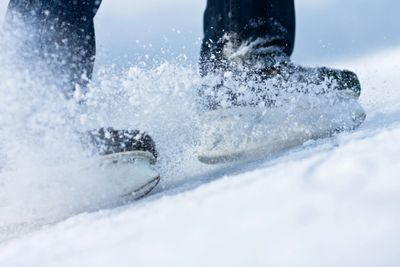 Hockey skates sliding to a hock stop, spraying ice