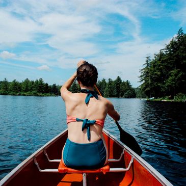 A rear view image of a female paddling a boat