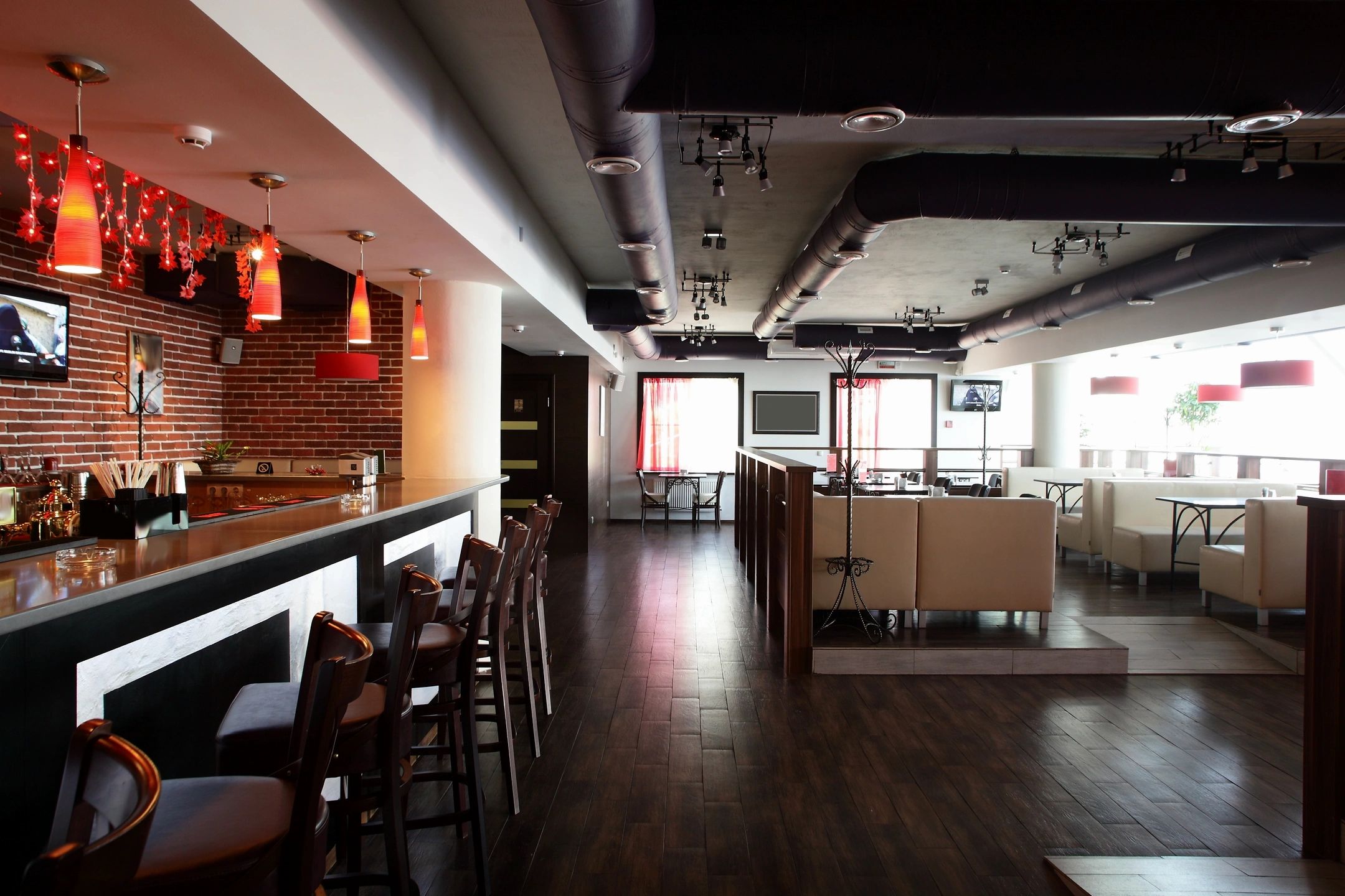 Empty modern bar with red lighting and wooden chairs.