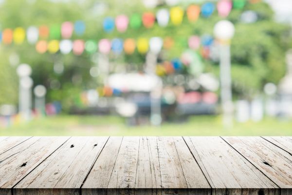 Empty wooden table with colorful blurred outdoor background.