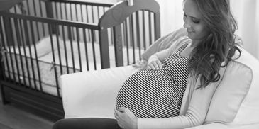 Mom sitting in the chair holding pregnant stomach- Geaux Dat Doula