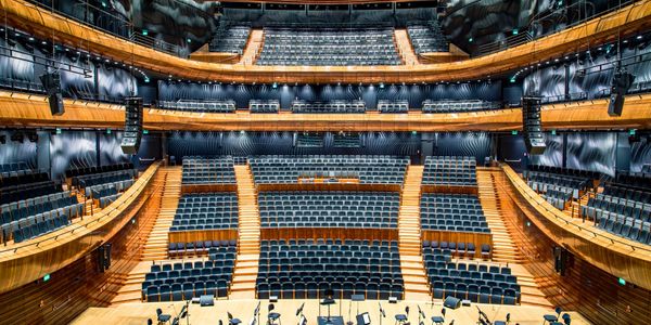 Empty modern concert hall with tiered seating and wooden interior.