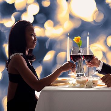 couple sitting at a table for a romantic dinner holding wine glasses