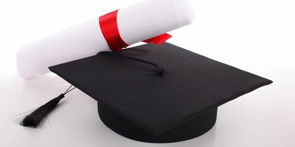 Black graduation cap with a diploma tied in red ribbon.