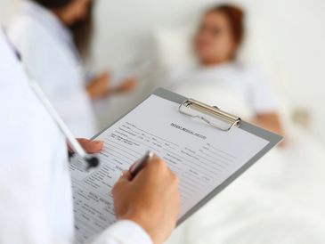 Doctor holding a pad writing on patient form