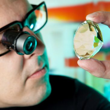 Man examining large gem with magnifying loupe.