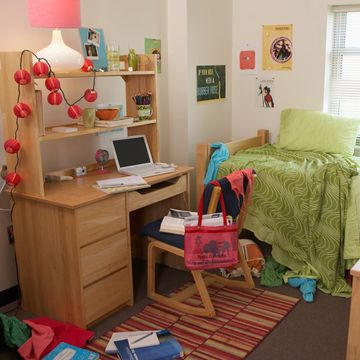 Cozy dorm room with a desk, bed, and colorful decorations.