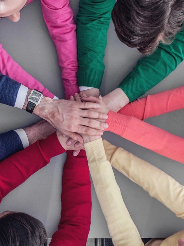 People joining hands in a teamwork gesture around a table.