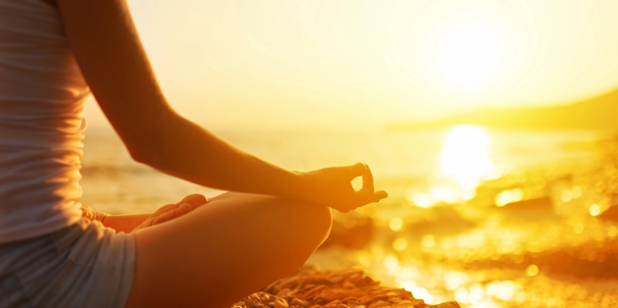 Lady sat in her meditation pose on the sunny beach, feeling calm and focused.