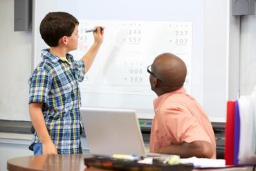 A student solving a math problem at a smart board. 