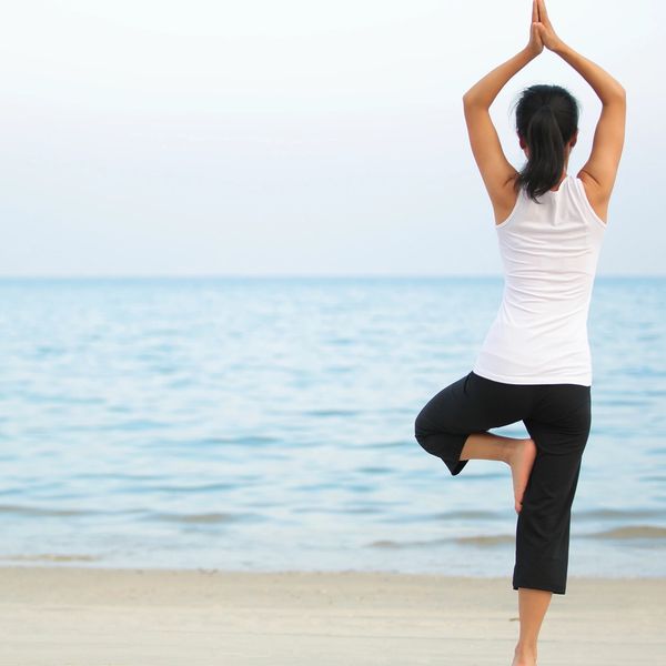 A woman in a yoga pose near the beach