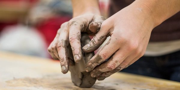 Hands shaping wet clay in a pottery session.