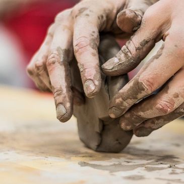 Hands shaping wet clay during pottery making.