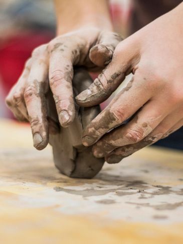 Hands shaping wet clay in pottery making.