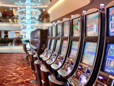 A row of slot machines in a casino with plush carpet flooring.