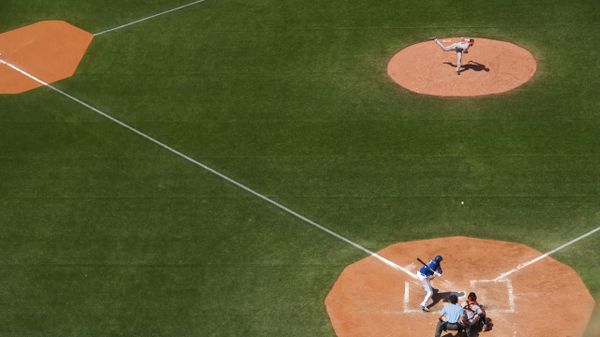 A pitcher throws a baseball to a batter on a sunny field.