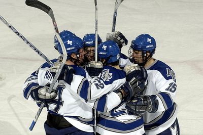 Photo of hockey team in a huddle with hockey sticks in the air. 