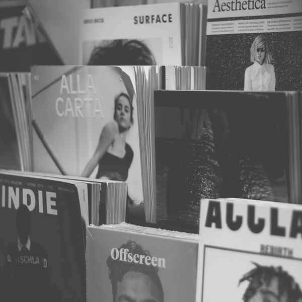 A display of various fashion and culture magazines on a rack.