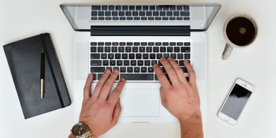 Laptop, coffee, typing, phone and diary - Administrator at work.