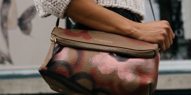 Close-up of a brown leather handbag with floral design.