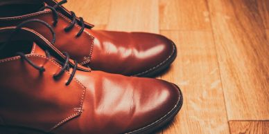 Close-up of polished brown leather shoes on a wooden floor.