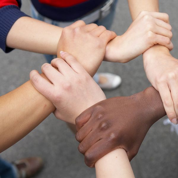Diverse hands joined together in a circle, symbolizing unity and cooperation.