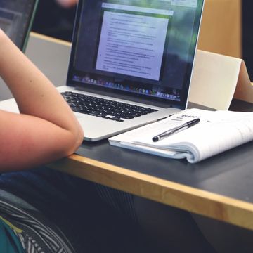 Person studying with laptop and notebook on desk.
