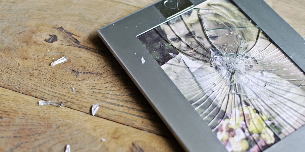 Wedding photo laying on wooden floor with broken glass