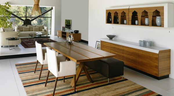 Modern dining room with wooden table, white chairs, and striped rug.