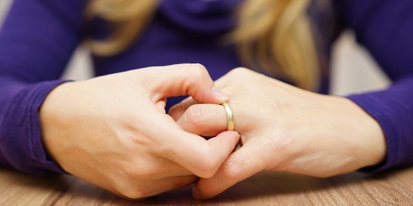 Woman sitting at table touching her wedding band