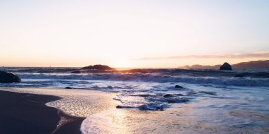 Serene beach at sunset with gentle waves.