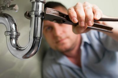 Plumber repairing a leak from the basin trap.