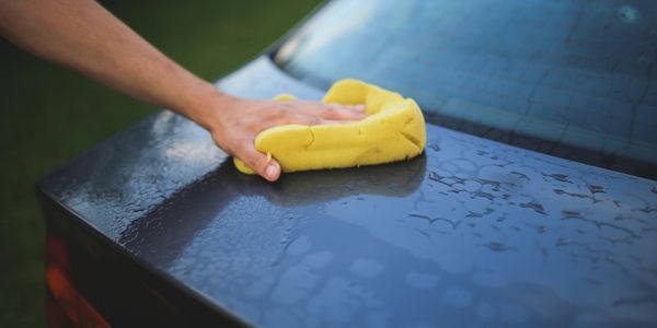 Person drying a car with a microfiber towel