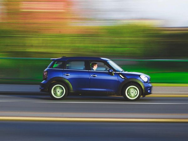 Blue car driving fast on a road with motion blur background.