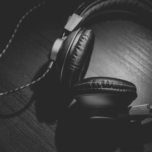 Black headphones resting on a wooden surface in monochrome.