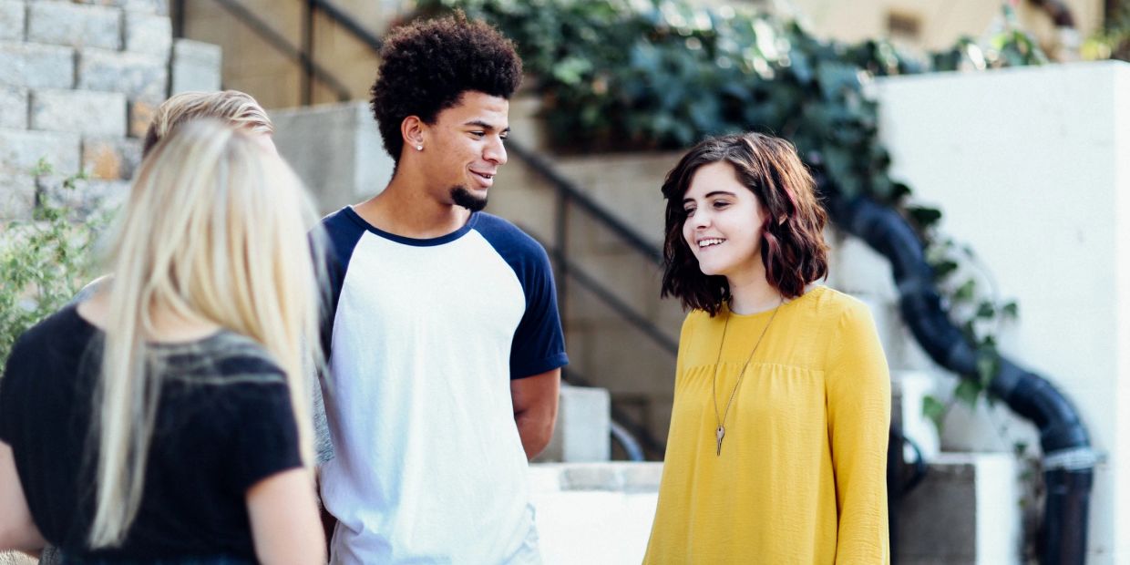 Jóvenes conversando y sonriendo en un ambiente al aire libre.