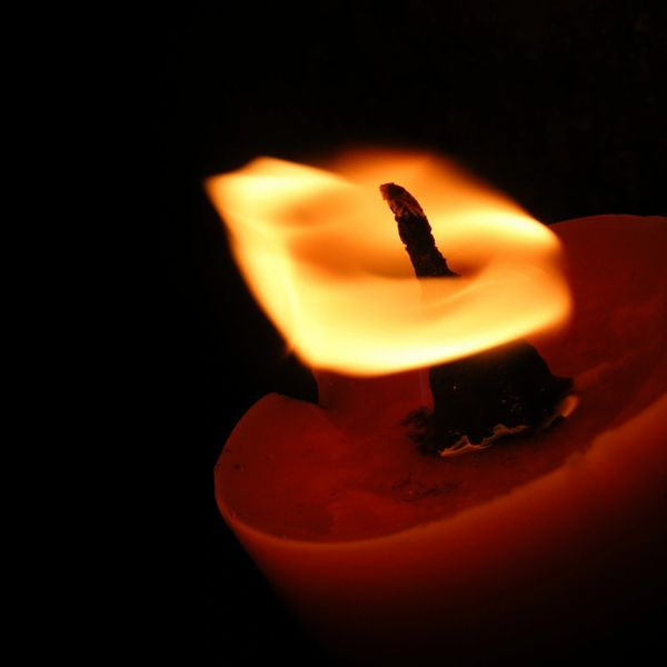 Close-up of a candle flame flickering in the dark.